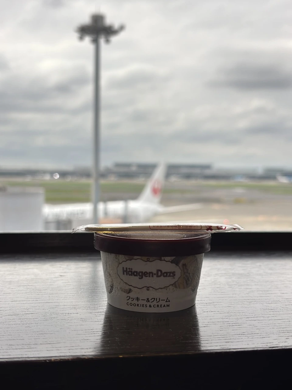 羽田空港のJALのラウンジの窓際に置いたハーゲンダッツ。外にJALの機体が見える