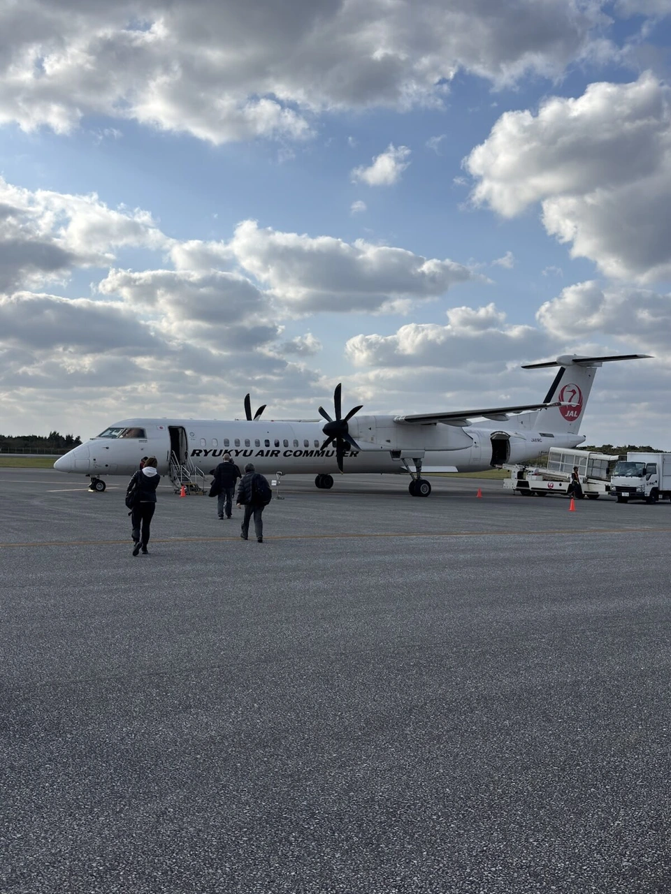 地方空港に止まるプロペラ機と歩いて向かう乗客