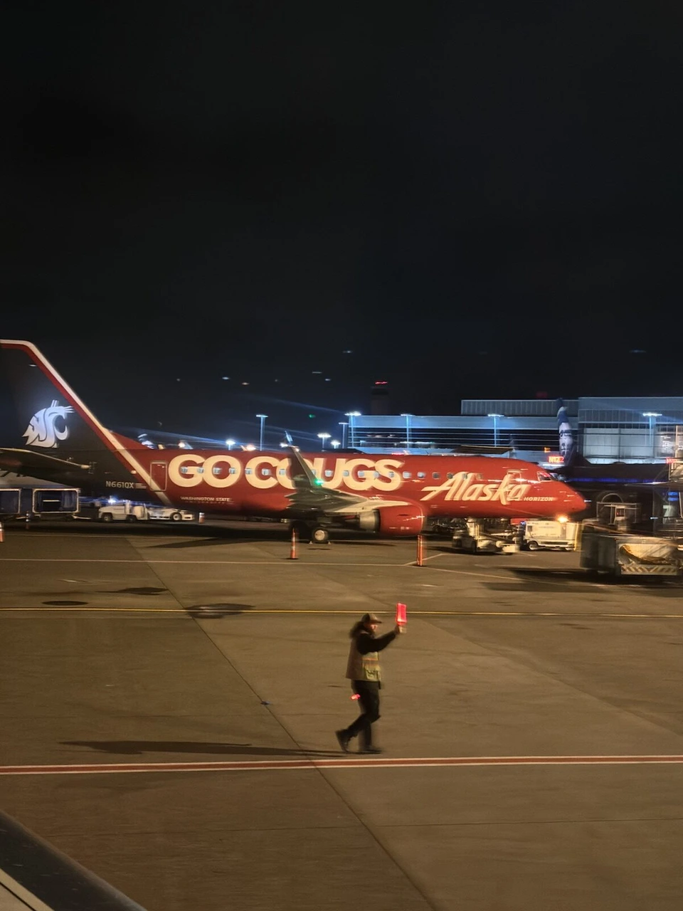 夜のシアトル空港に止まるGO COUGSと書かれた特別塗装のアラスカ航空機