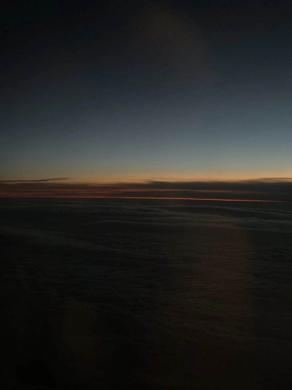 暗くなった機窓に残るオレンジ色の夕焼け