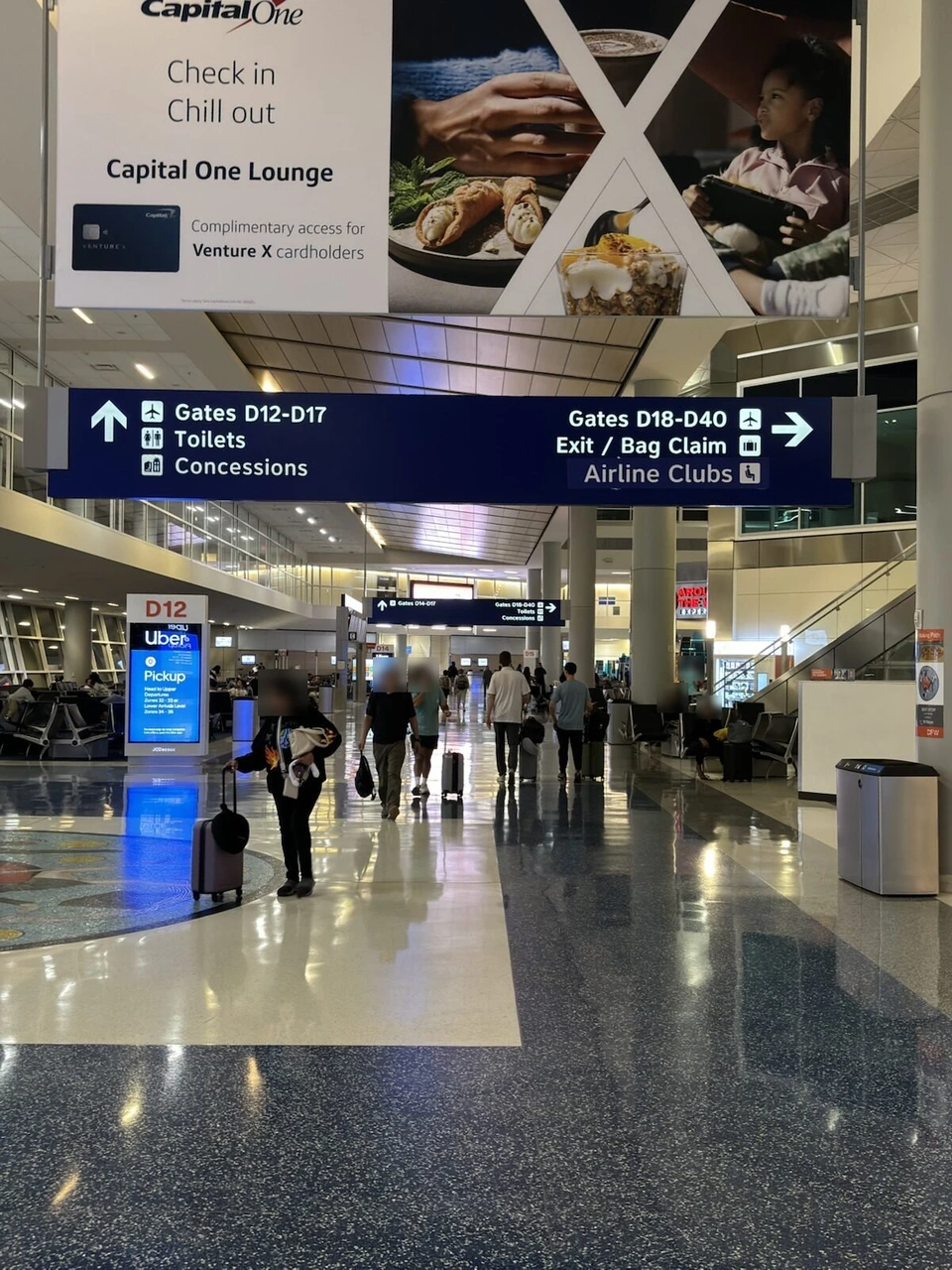 ダラス空港ターミナルDの通路。Capital One Loungeの広告とゲートD12-D17の案内