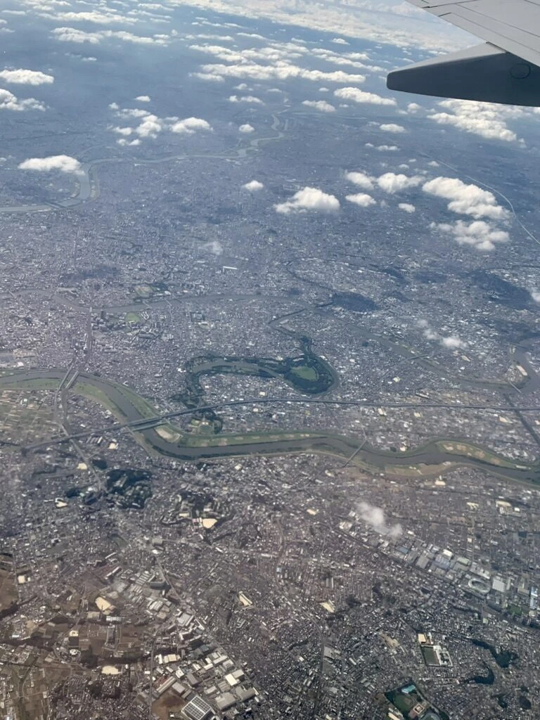 上空から見た東京の市街地と川、主翼の端