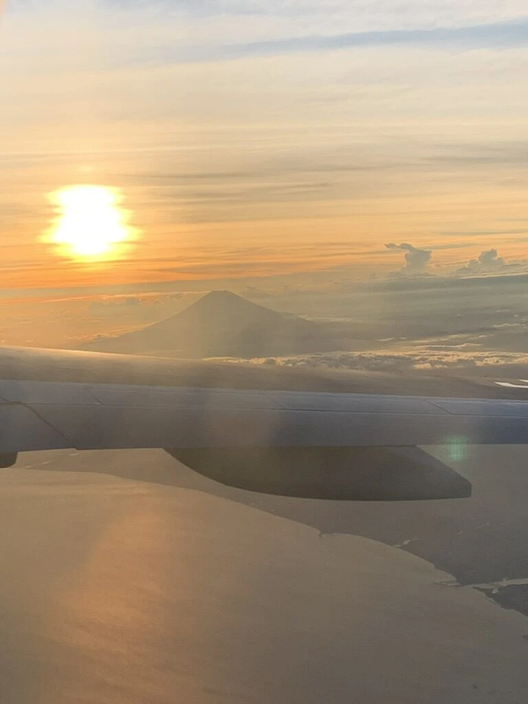 ANA1097便の機窓から見た夕日の下の富士山のシルエット