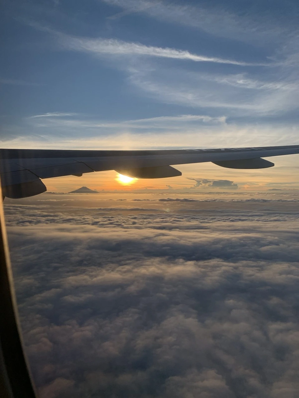 ANA1097便の機窓。主翼の向こうに沈む夕日と、オレンジ色に染まる雲海