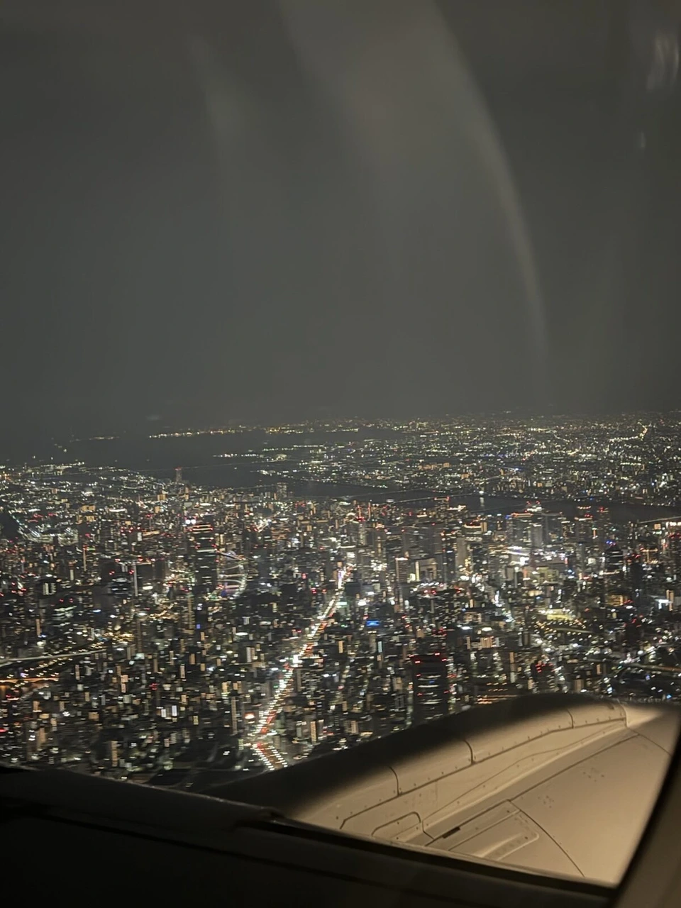 JL2176の窓から見た大阪の夜景。街の明かりが広がり、手前に主翼