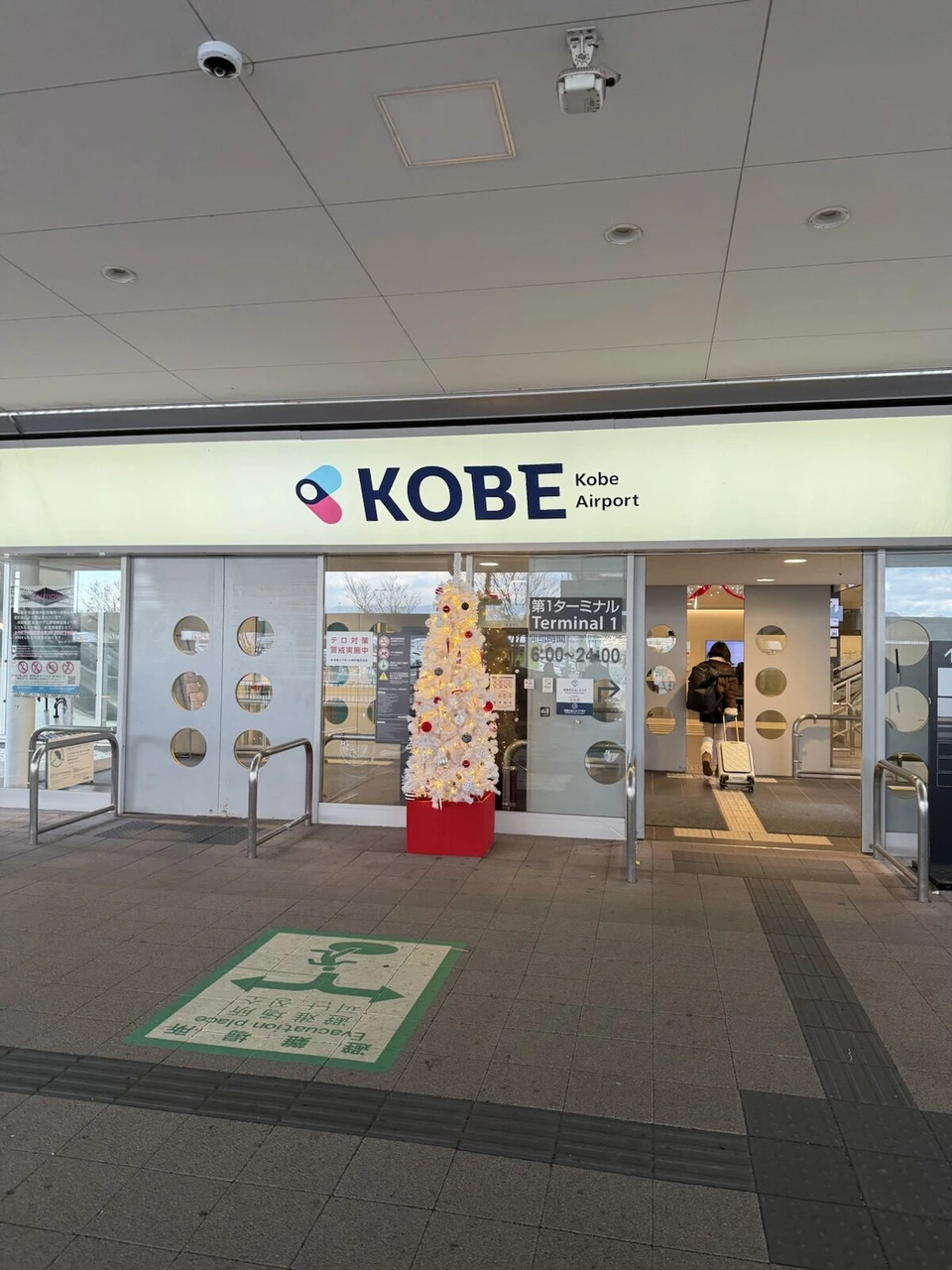 神戸空港ターミナルの入口。KOBE Airportの看板と白いクリスマスツリー