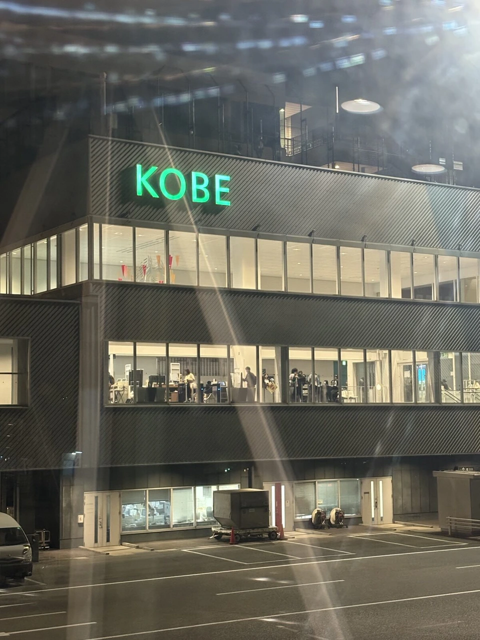 機内の窓から見た夜の神戸空港ターミナル。緑色のKOBEの文字