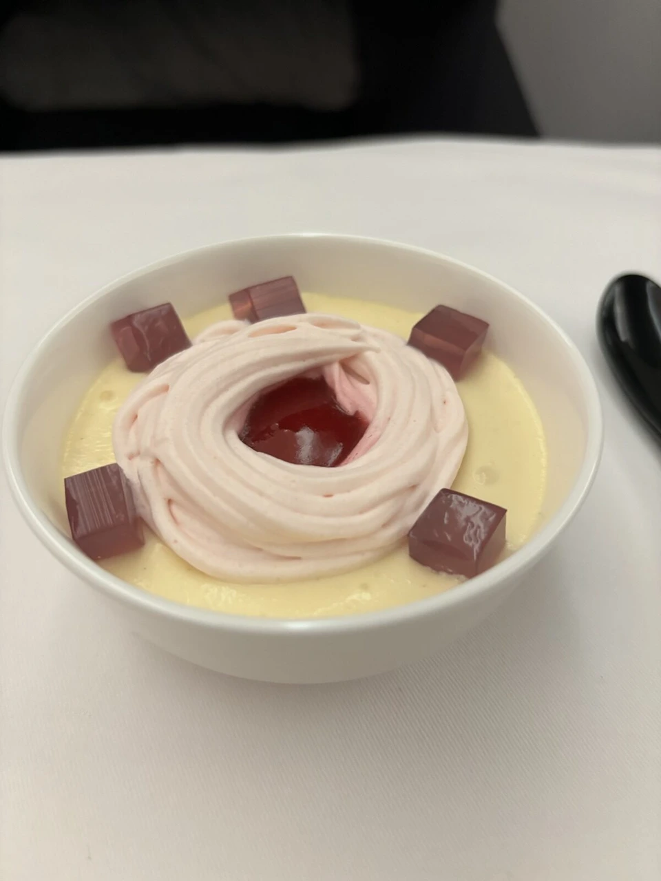 NH801ビジネスクラスのデザート。ピンク色のクリームを絞ったプリンのようなものに、赤いゼリーの角切り