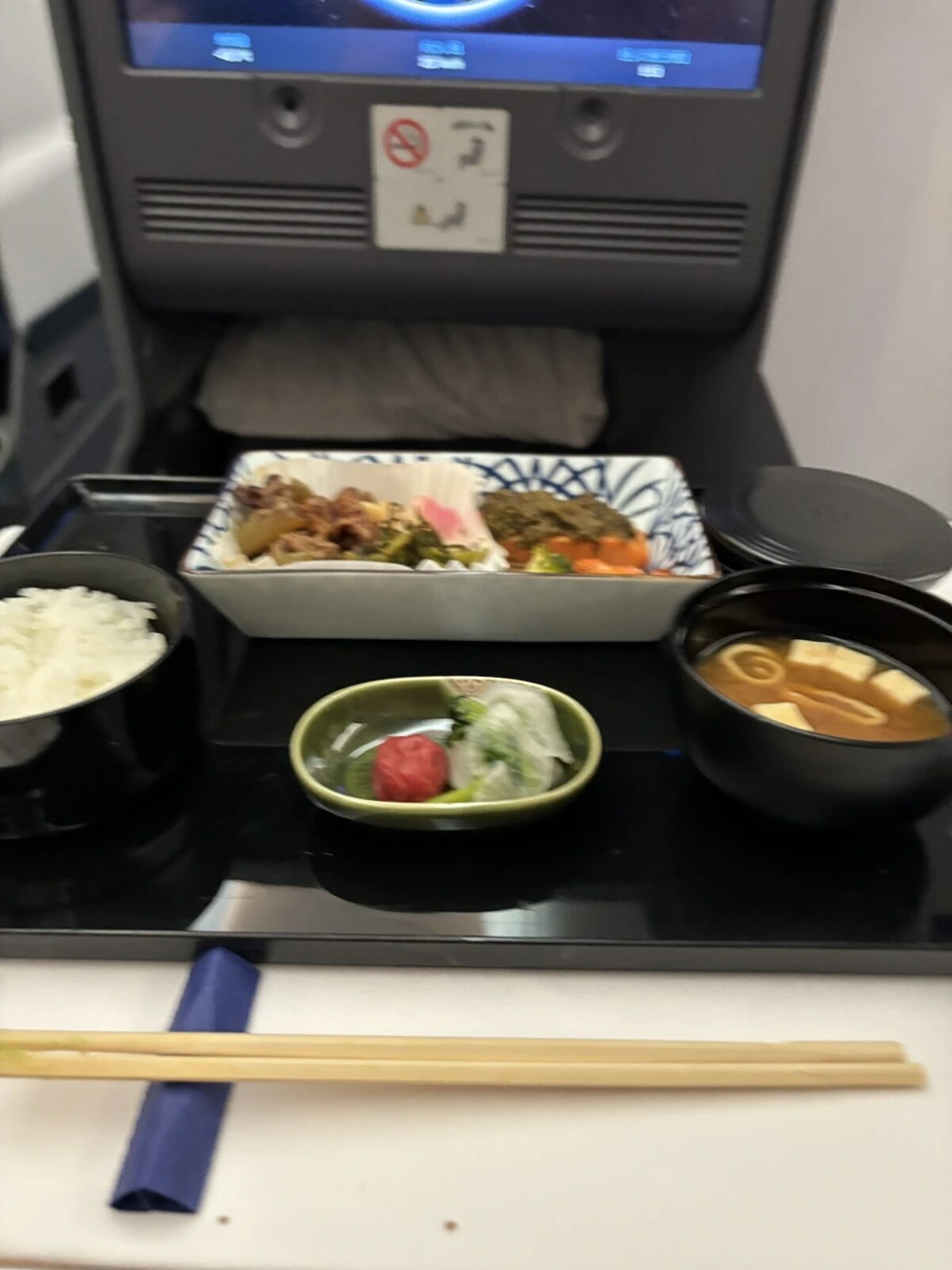 NH801ビジネスクラスの和食の主菜。ご飯、味噌汁、梅干しの小鉢、肉や野菜の入った角皿