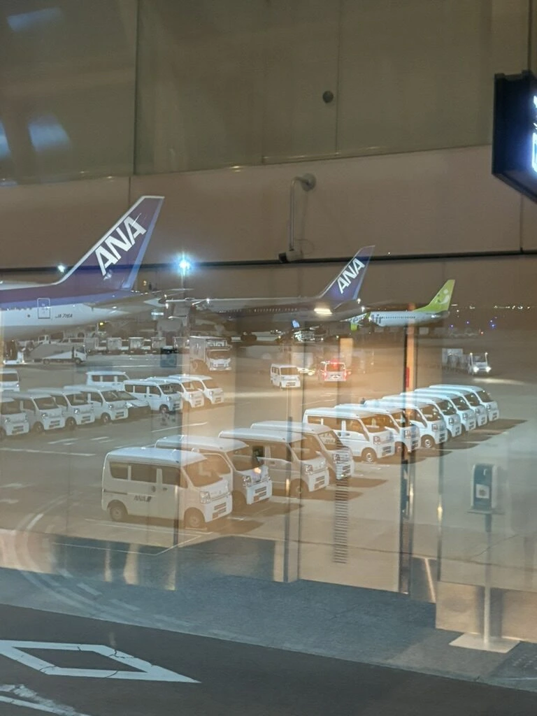 羽田空港のガラス越しに見えるANA機と、夜の駐機場