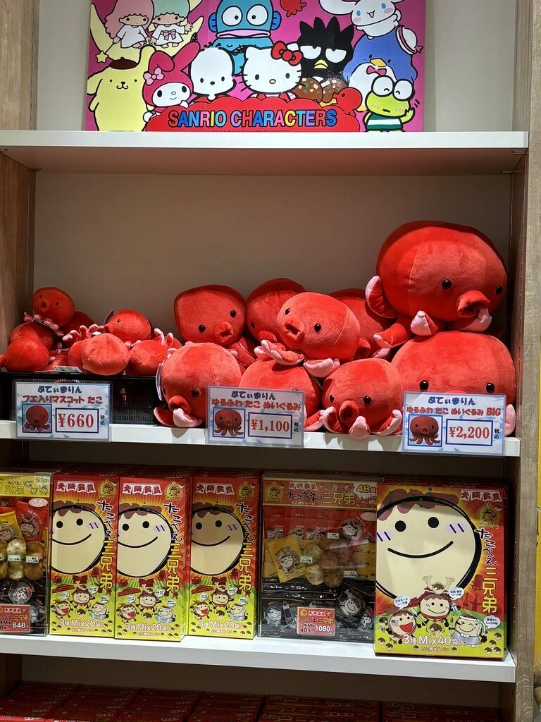 空港の売店に並ぶ赤いたこのぬいぐるみとたこ焼き風の菓子