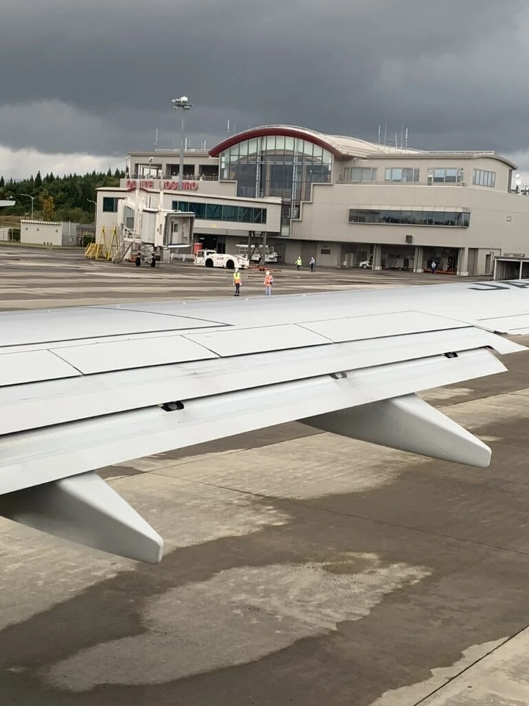 機内から見た大館能代空港のターミナルと主翼。空は暗い雲