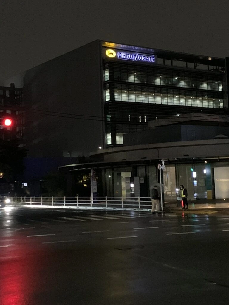 雨の夜の交差点と、ヤマト運輸の羽田クロノゲートの建物
