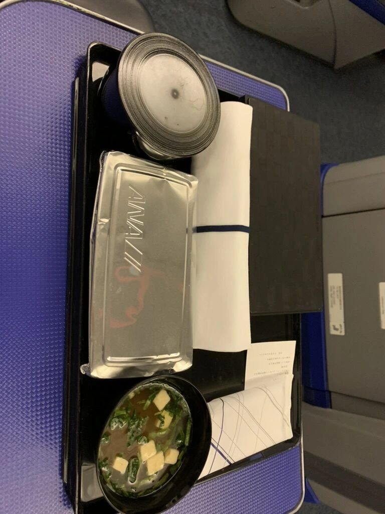 上から見たふた付きのトレー。紙ナプキン、ふたの付いたご飯のお椀、味噌汁