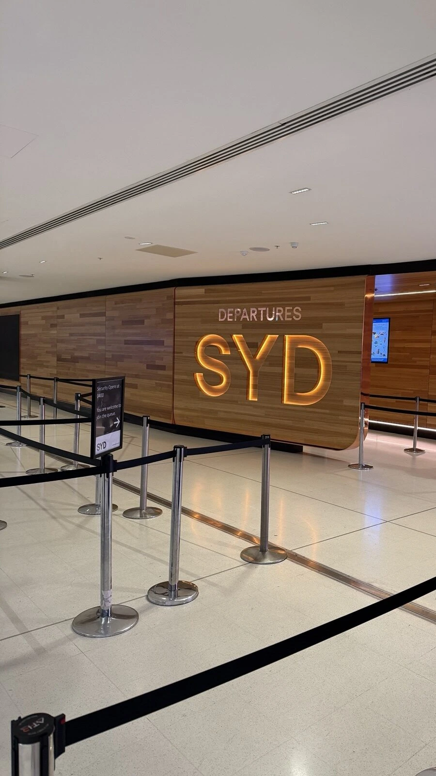 シドニー空港国際線の出発口。木の壁にDEPARTURES SYDの文字