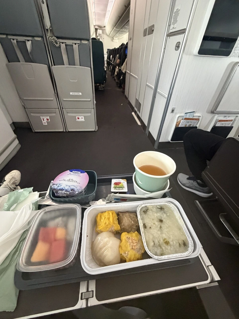 CX596の機内食のトレーと、通路側から見たエコノミーの客室