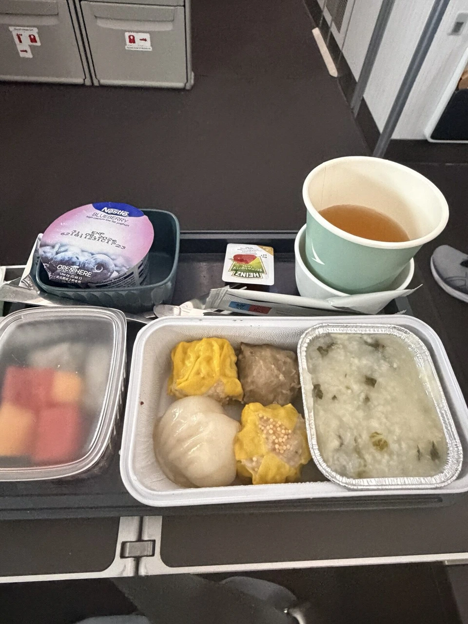 CX596のエコノミーの機内食。焼売、ハーガウ、ザーサイ入りのお粥、フルーツ、ブルーベリーヨーグルト、紅茶
