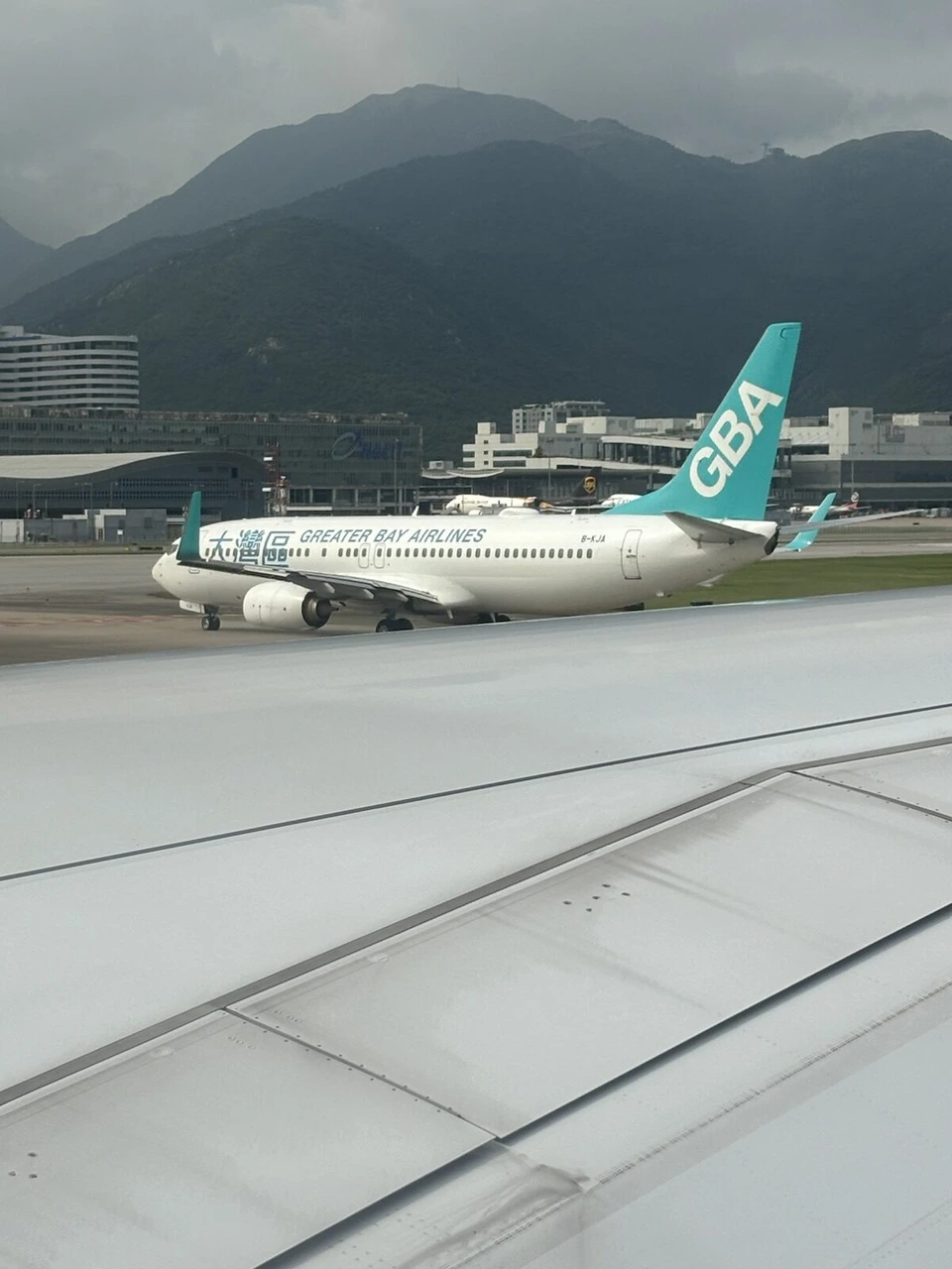 香港空港の誘導路を走るグレーターベイ航空のボーイング737と、後ろの山