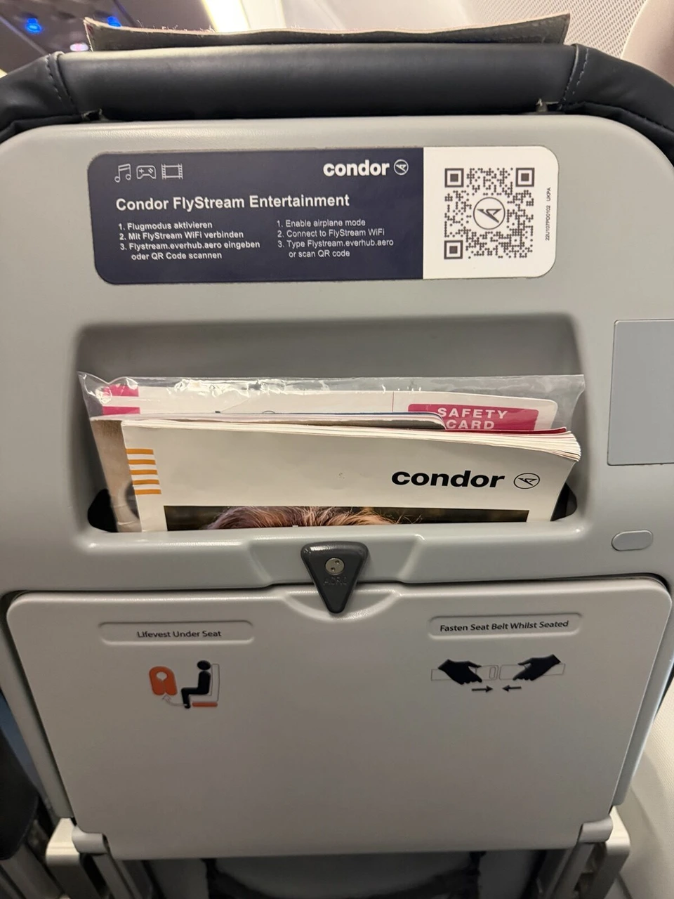 コンドル航空の座席の背面。Condor FlyStream Entertainmentの案内とQRコード、ポケットの安全のしおり