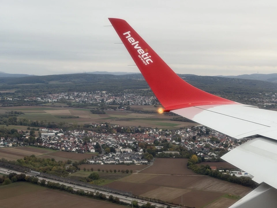 フランクフルト空港へ降りていく機内から見た、赤いウイングレットと住宅地、畑