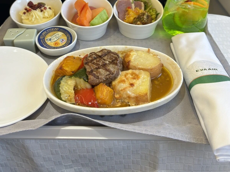 エバー航空BR282ビジネスクラスの機内食。牛ヒレのグリルと野菜、チーズを載せて焼いたポテト、小鉢3つと緑色のドリンク