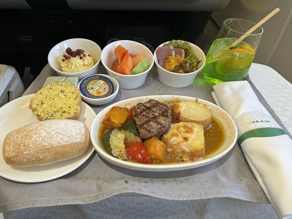 機内食を正面から。パン2種類、牛肉のグリル、小鉢3つ、エバー航空のナプキン