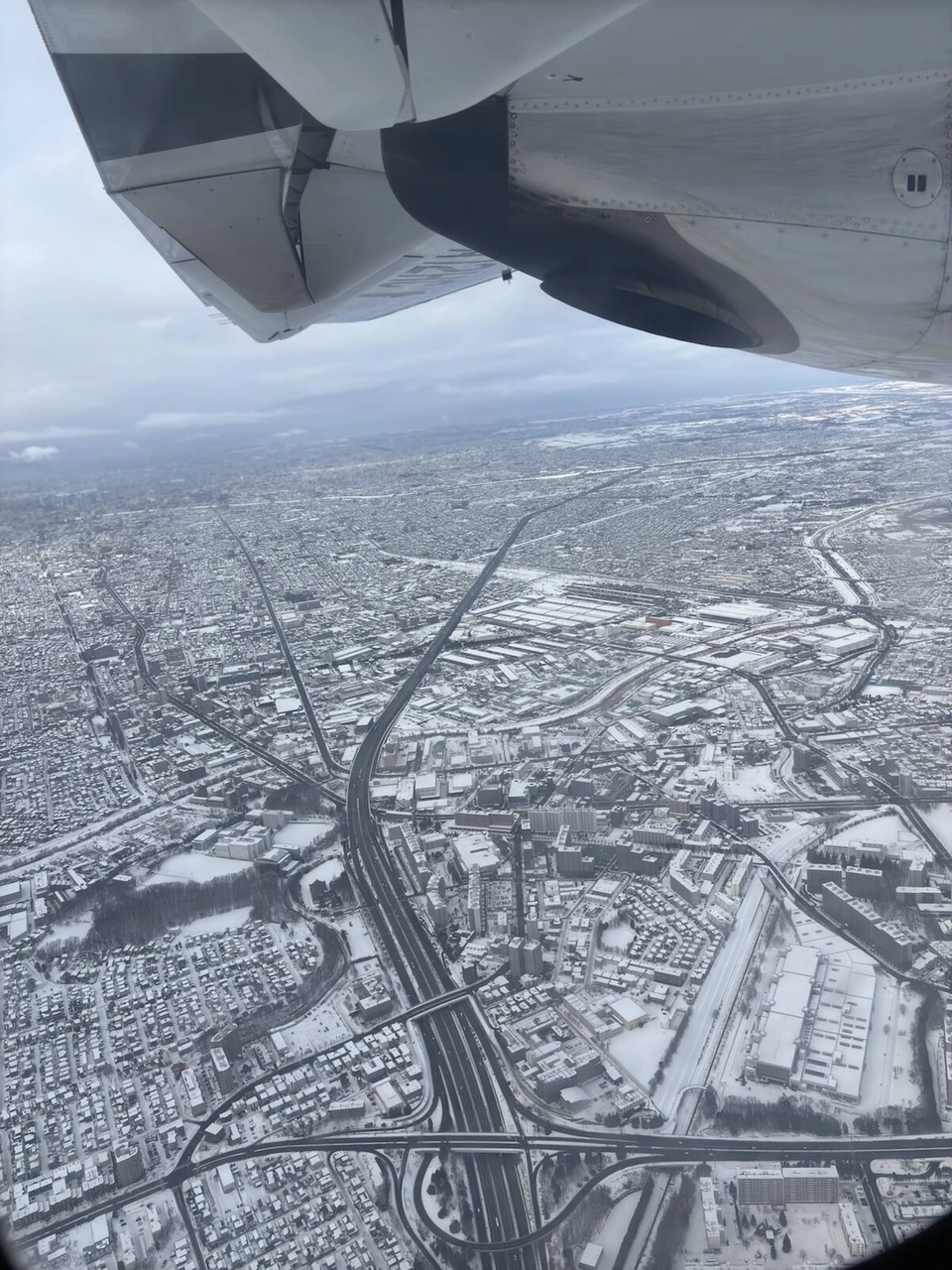 着陸前の機窓から見た雪の札幌。高速道路と住宅街、上にATRの主翼