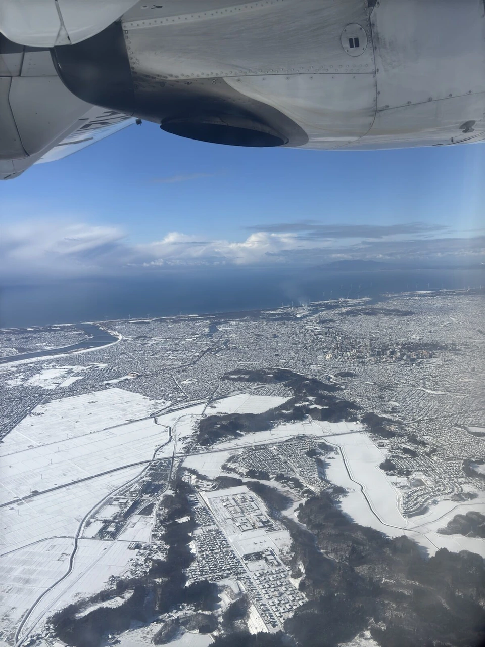 秋田を離陸したJL2824(ATR42-600)の主翼の下に見える、雪の秋田の海岸線