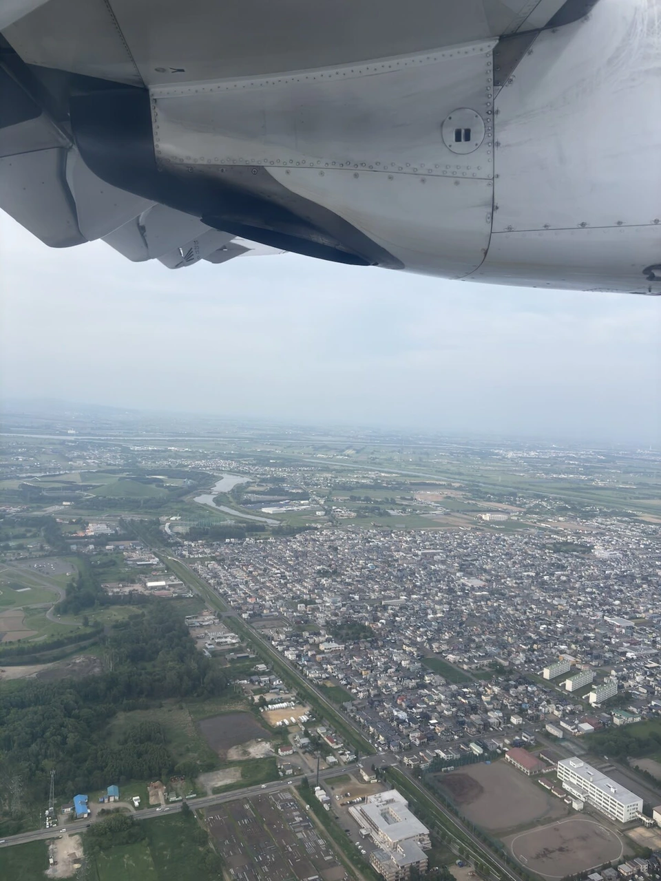 丘珠を離陸したATRの主翼の下に広がる札幌近郊の住宅地と畑