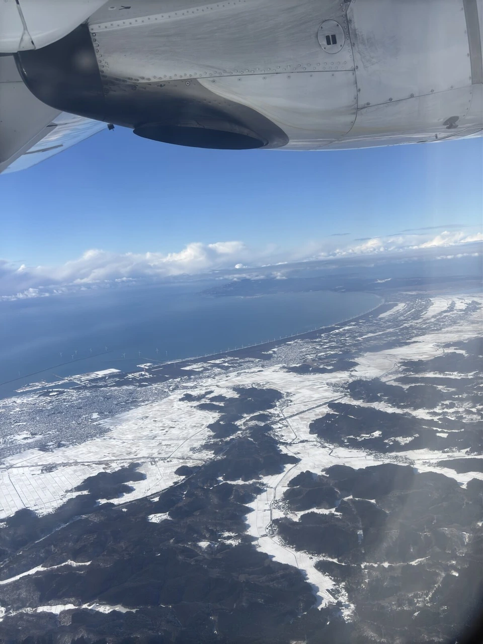 機窓から見た雪の海岸線と日本海。上にATRの主翼とエンジン