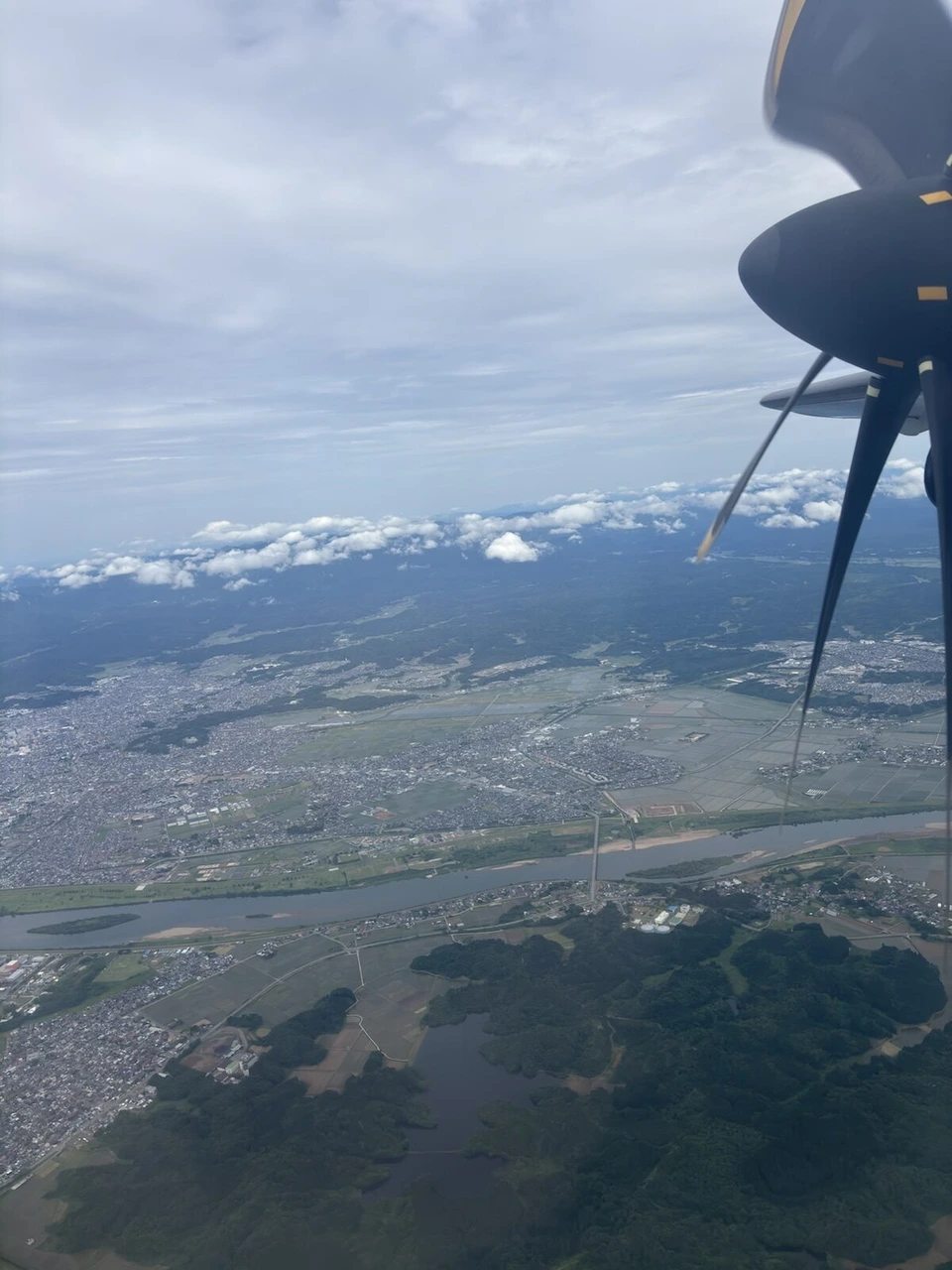 JL2824のATR42-600のプロペラ越しに見た秋田の市街地と川、雲