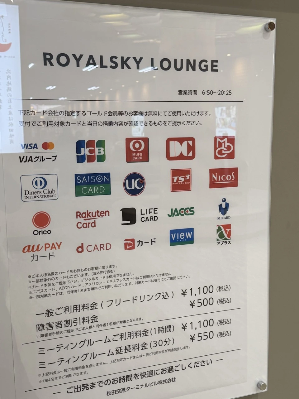 秋田空港のカードラウンジROYALSKY LOUNGEの案内板。営業時間6:50〜20:25、対象のカード会社のロゴ、一般料金1,100円