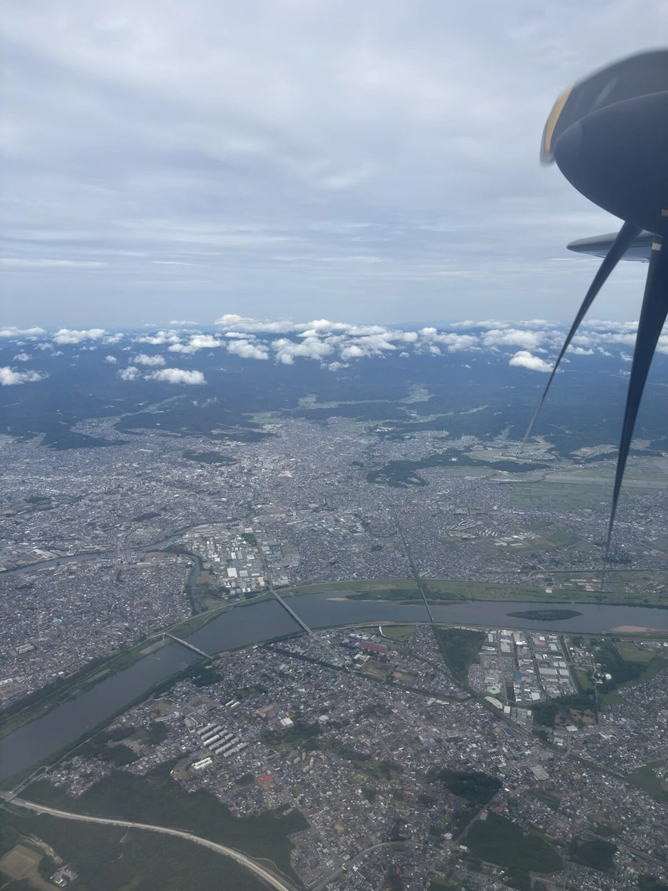 プロペラの向こうに広がる秋田の市街地と蛇行する川