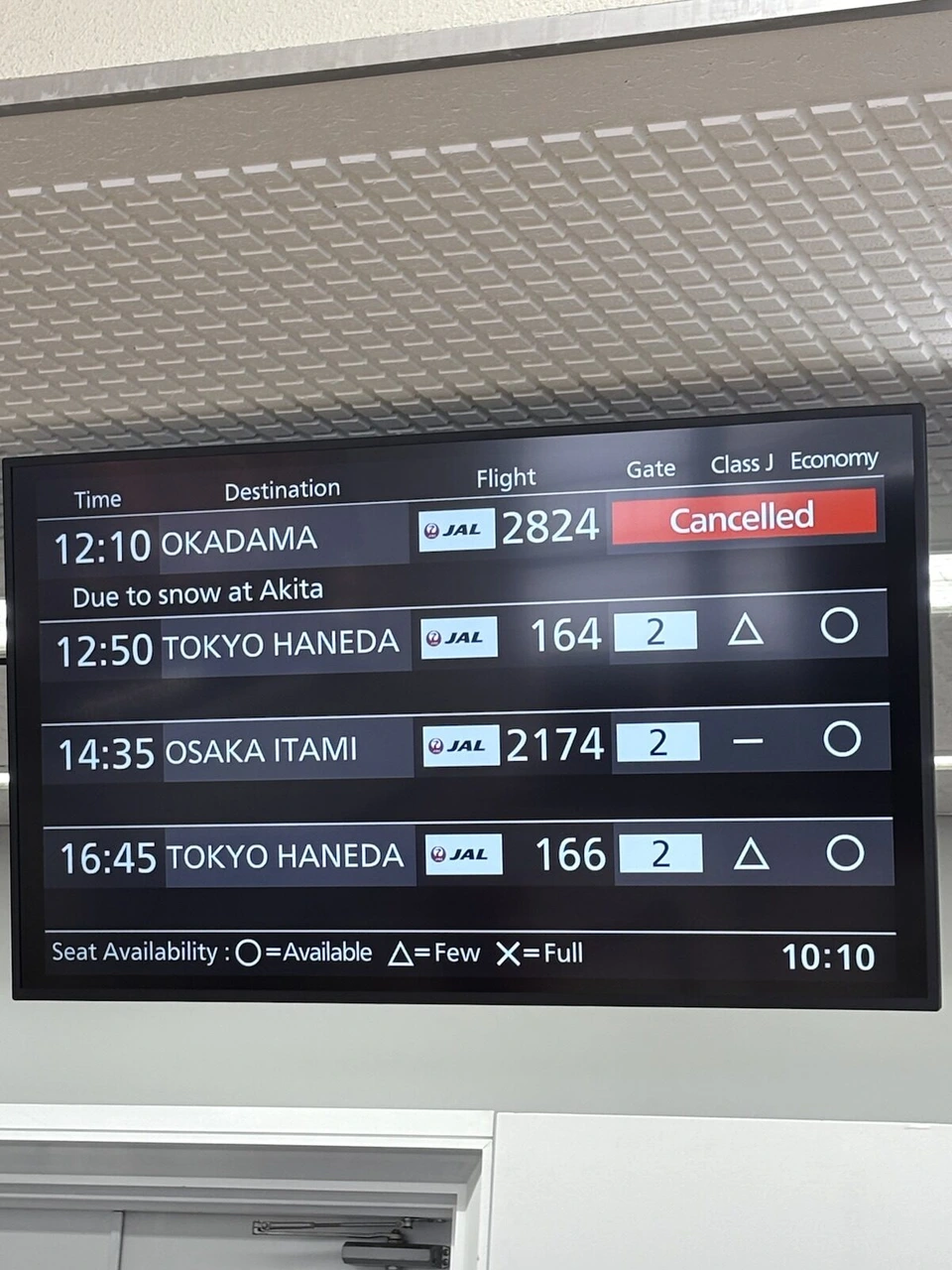 秋田空港の出発案内。OKADAMA 2824 Cancelled、Due to snow at Akita の表示