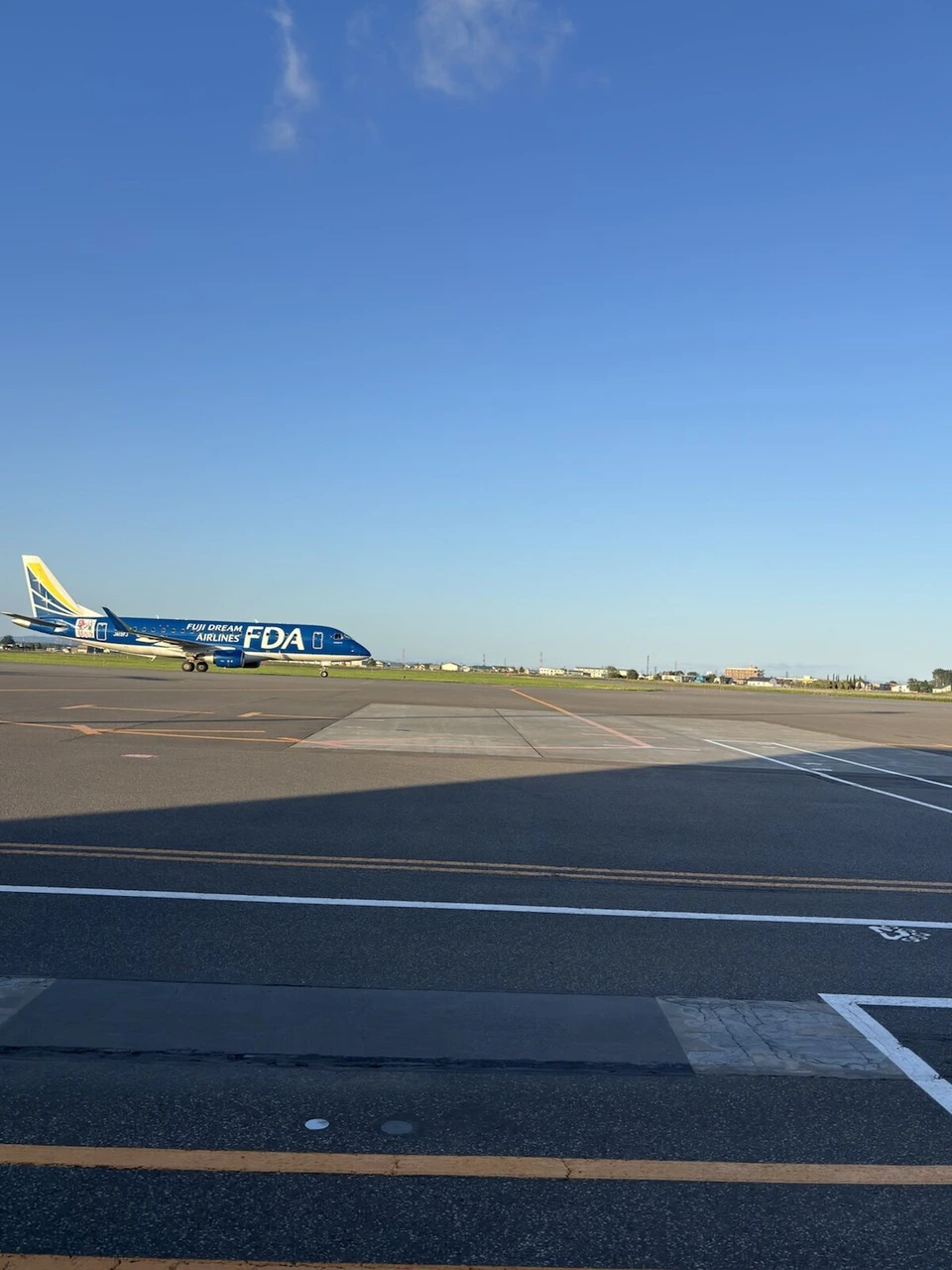 夕方の丘珠空港の誘導路を走る青いFDAのエンブラエル機