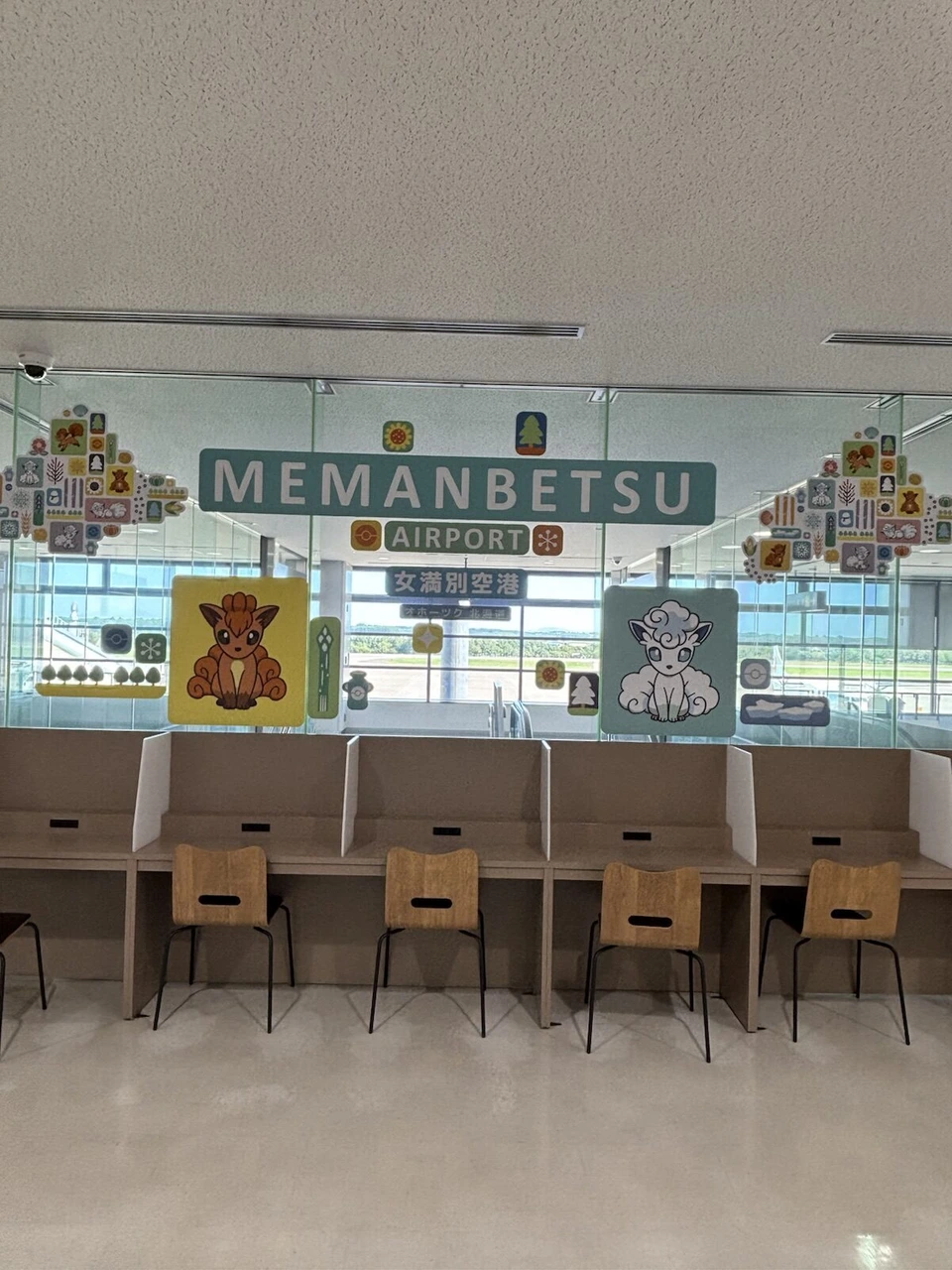 MEMANBETSU AIRPORTの看板と、ロコンとアローラロコンの絵のパネル、その下の机と椅子