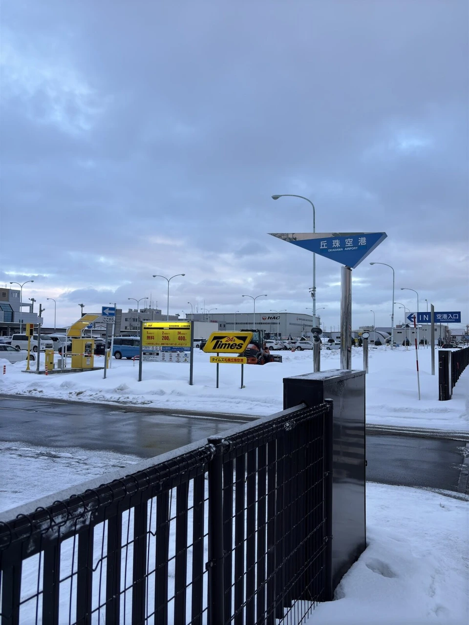 雪の残る丘珠空港の前の道路と、空港の案内標識