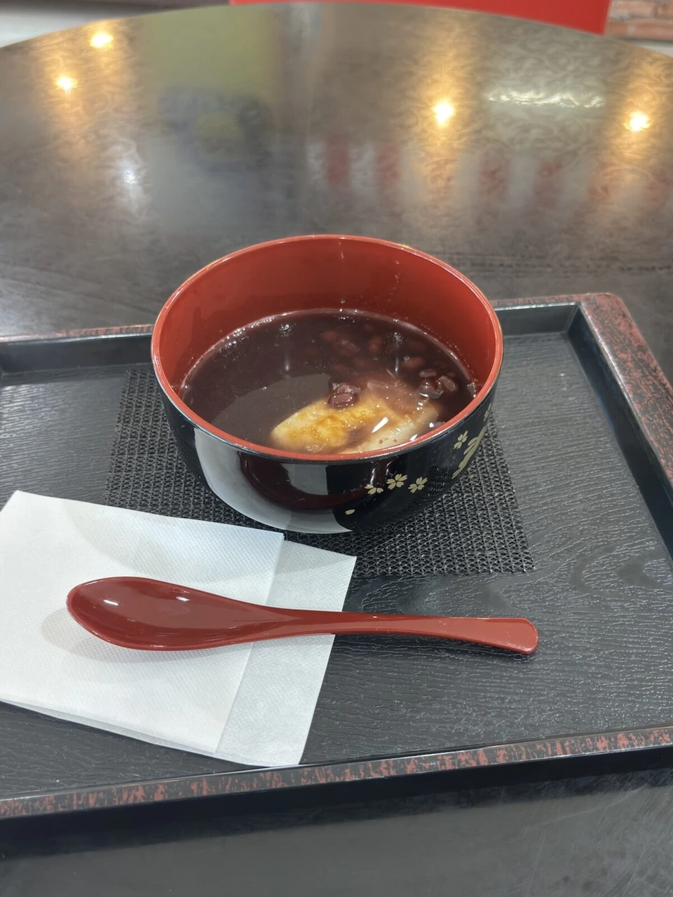 出雲空港の店で出された、お盆にのったぜんざいと赤いスプーン