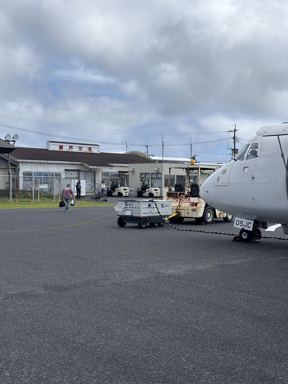 喜界空港の駐機場に止まるJL3785のATR42-600(JA05JC)と、奥の小さなターミナル