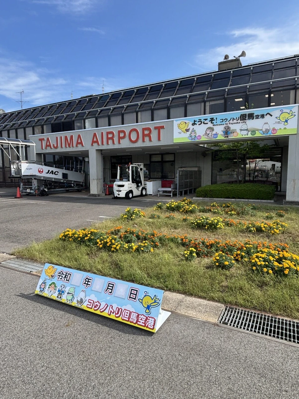 但馬空港のターミナルの前の花壇と、コウノトリ但馬空港と書かれた看板