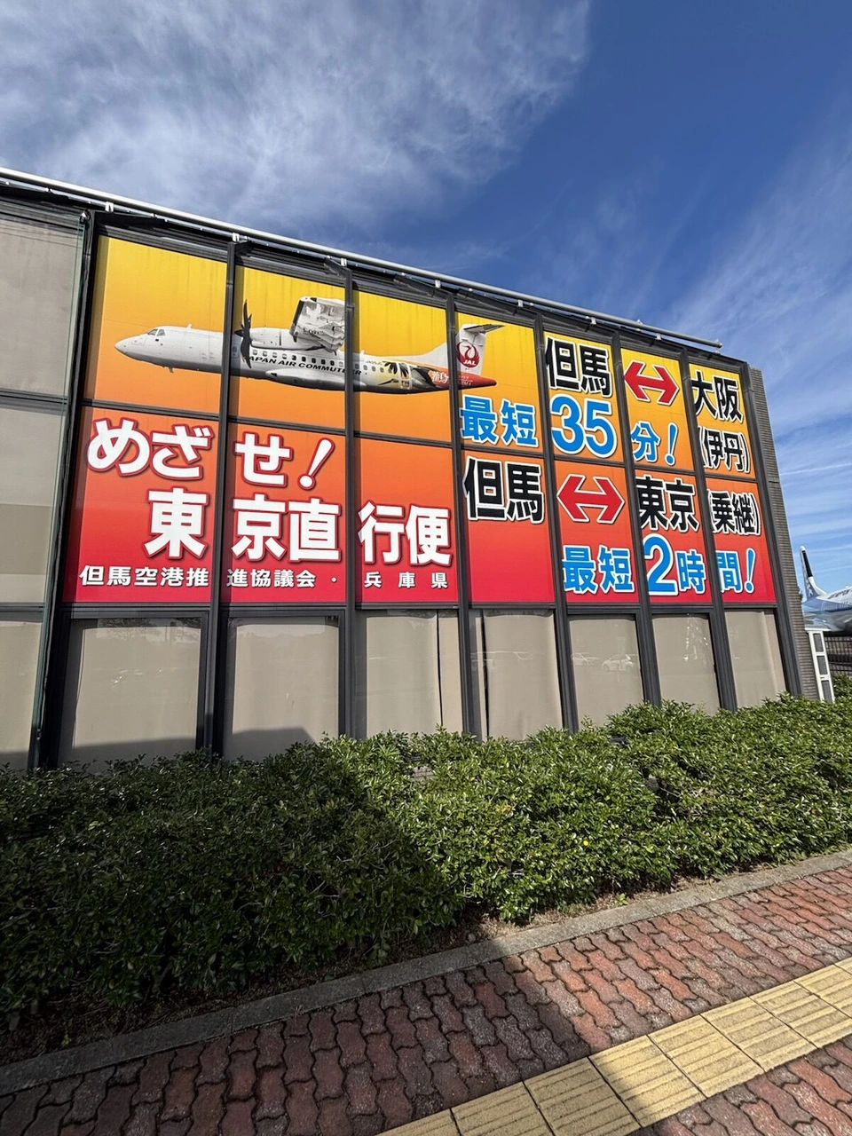 但馬空港の建物の壁の大きな広告。但馬⇔大阪最短35分、但馬⇔東京乗継最短2時間