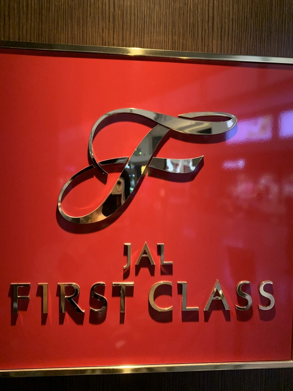 赤い壁に金色のFのマークとJAL FIRST CLASSの文字