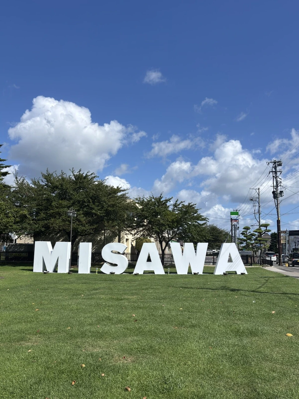 青空と芝生の上に立つ、白いMISAWAの文字のモニュメント