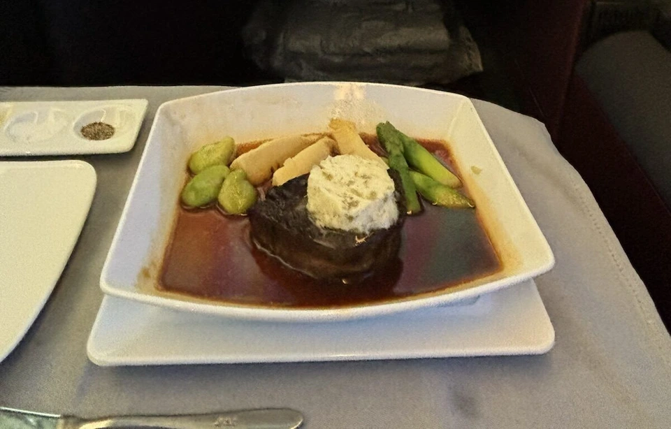 JL12ビジネスクラスのメインの肉料理。濃い色のソースの牛肉にアスパラ、たけのこ、そら豆