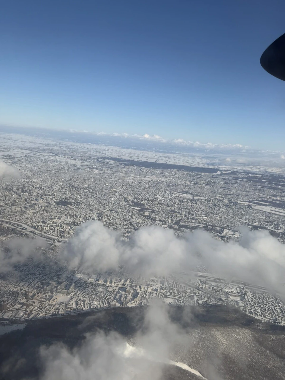 JL2824の機窓から見た雪の札幌市街。右上にATRのプロペラの先