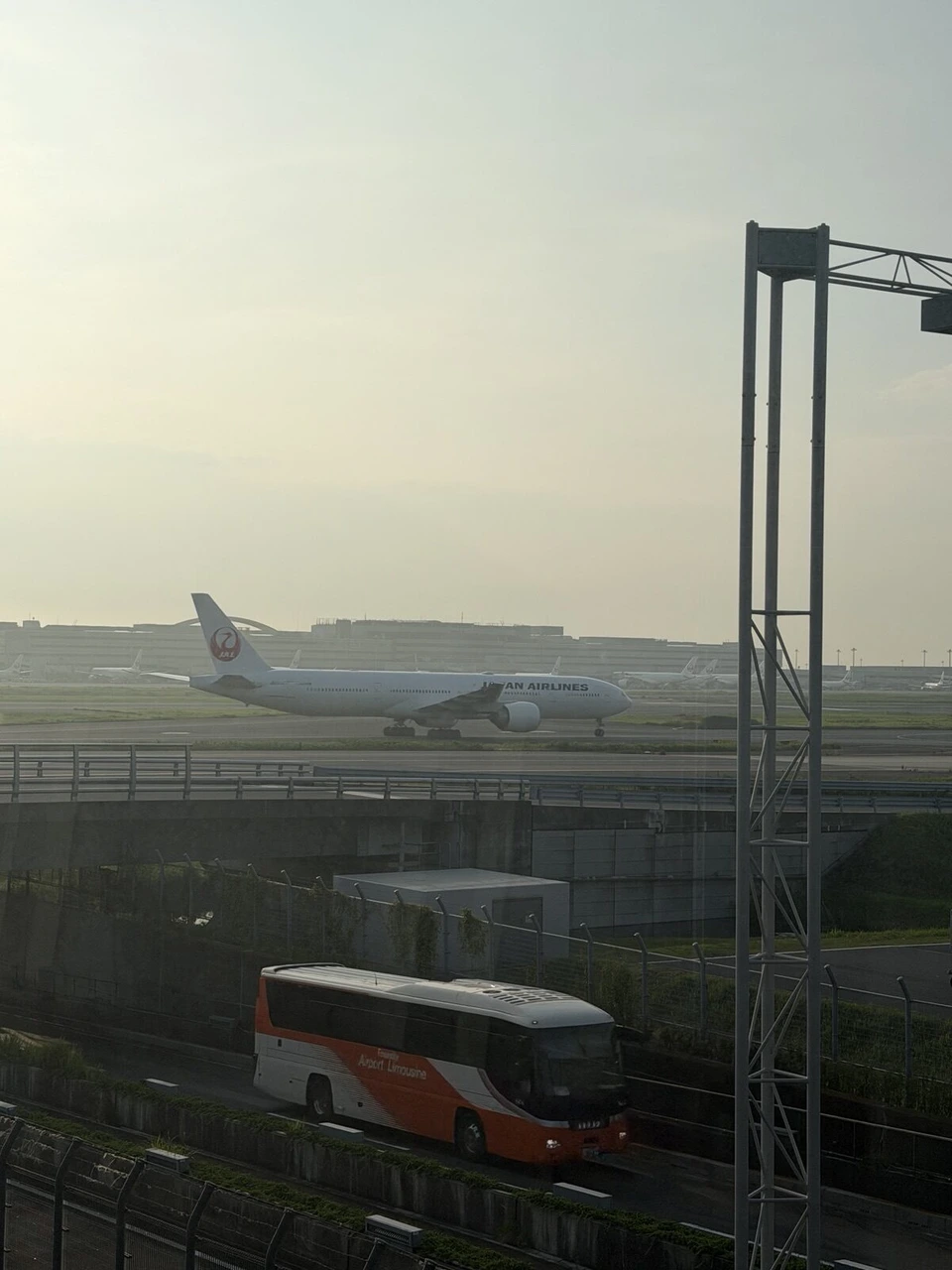 早朝の羽田空港。滑走路のJAL機と手前のバス