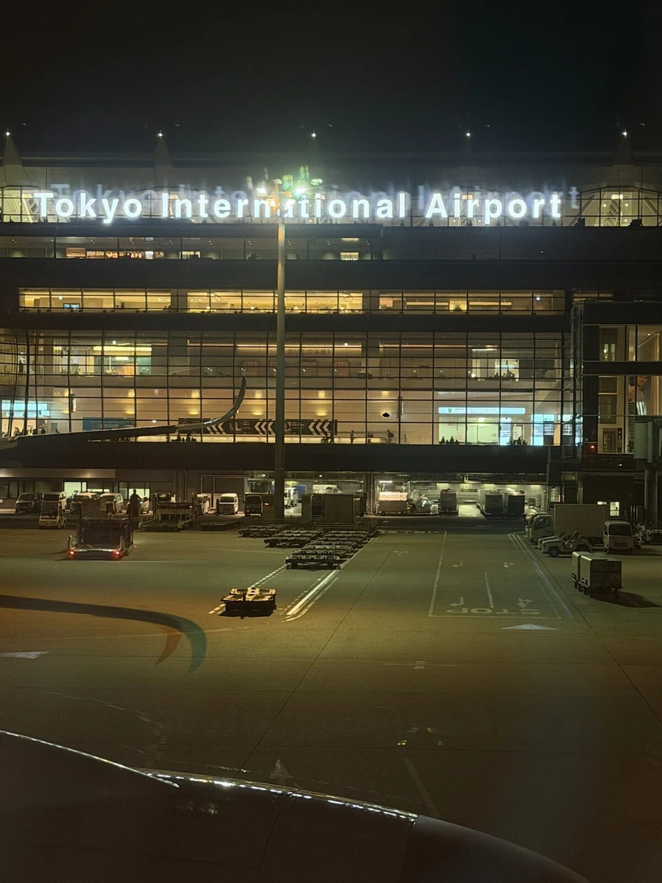 機内から見た夜の羽田空港第3ターミナル。Tokyo International Airportの文字