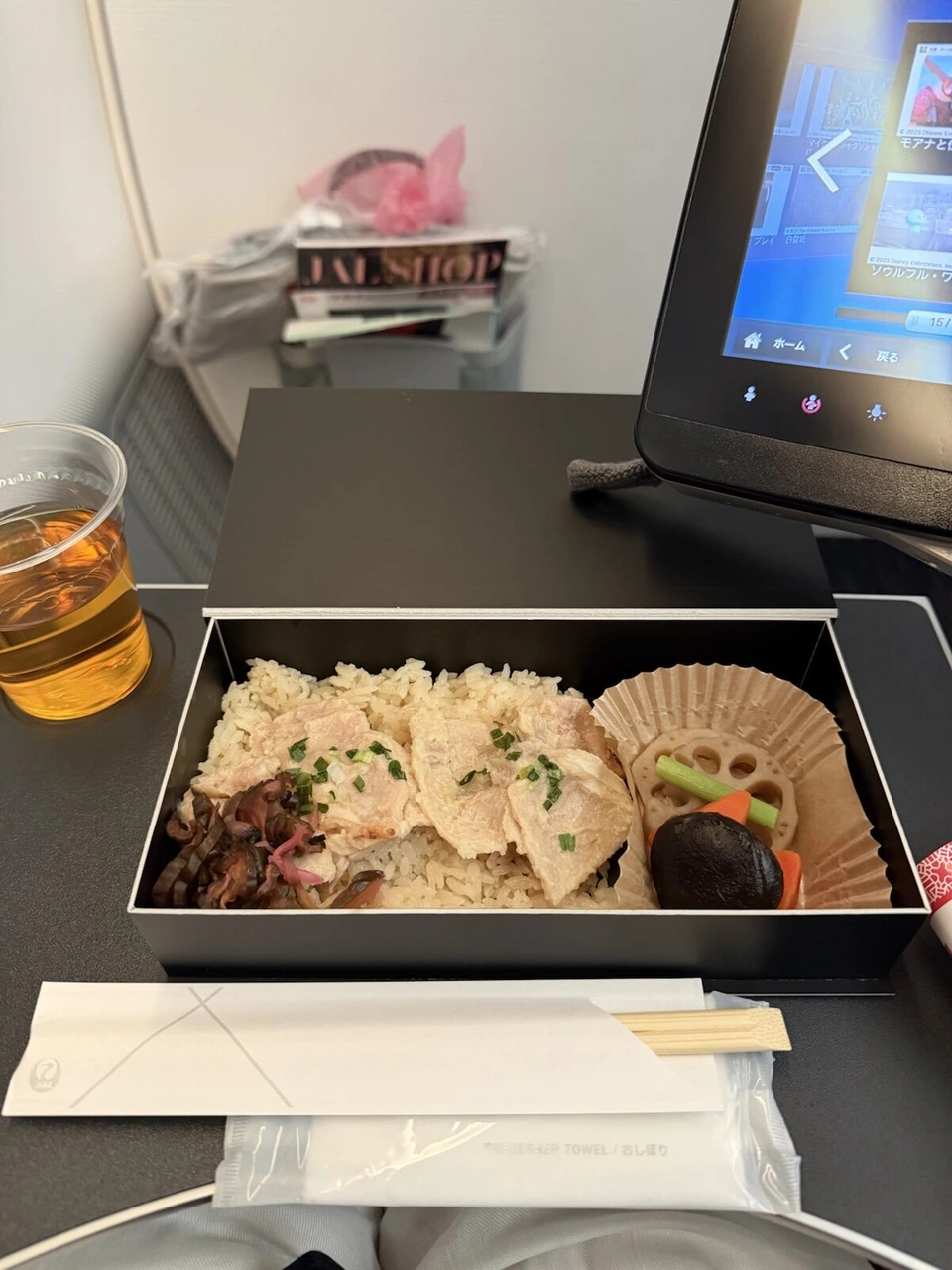 JL95の機内食「おもてなし御膳」の箱を開けたところ。茶飯の上に豚ロース、柴漬け、レンコンとシイタケの煮物