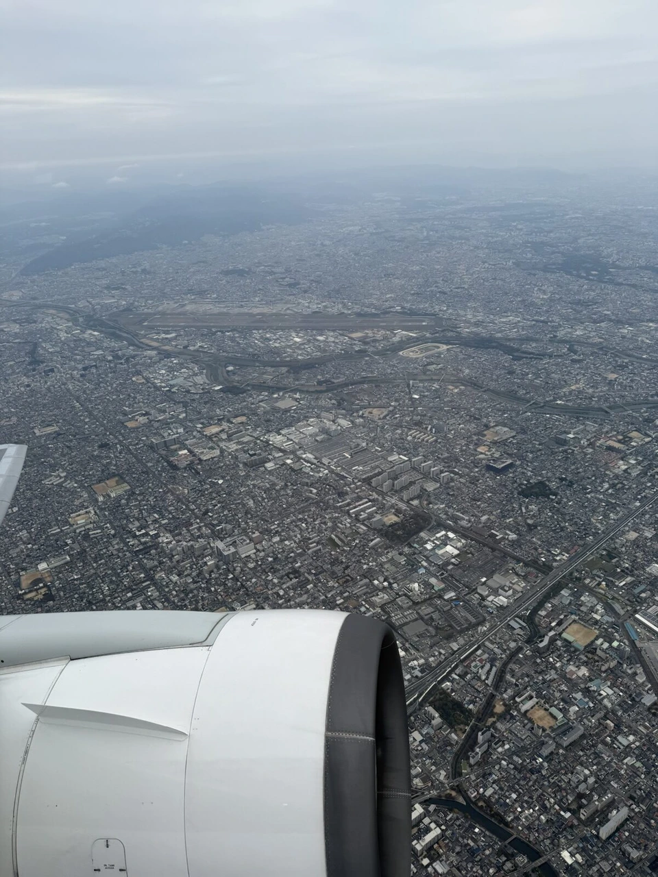 JL112で伊丹空港を離陸した直後の機窓。エンジンの向こうに大阪の街並み