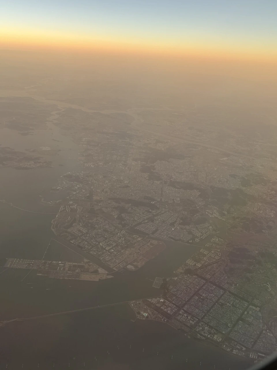 着陸の2時間ほど前に窓から見た夕焼けと、海沿いに広がる街並み